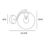 Elegant curved brass wall light, glass globe radiates soft, stylish illumination; vintage appeal.