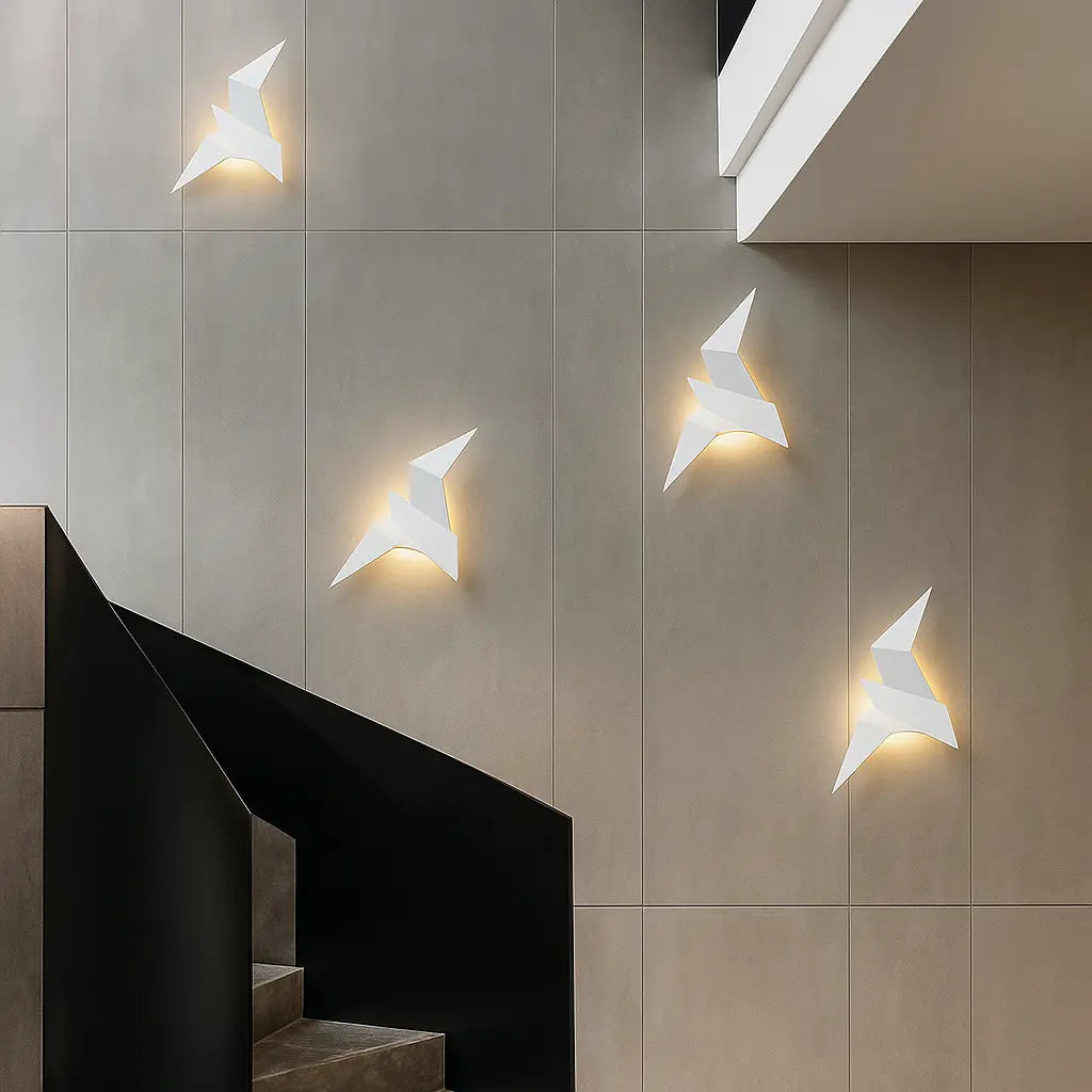 Geometric white bird-shaped wall lights emit a warm glow; metal and acrylic sculptural fixtures.