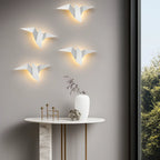 Four Origami LED wall lights with sculptural metal and acrylic design emit a soft glow.