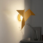 Gold origami bird-shaped LED wall light, metal and acrylic, casting a warm glow.