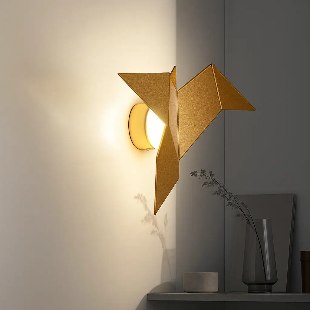 Gold origami bird-shaped LED wall light, metal and acrylic, casting a warm glow.
