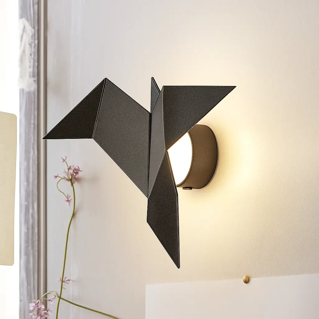 Black origami bird-shaped LED wall light emits a gentle glow through its acrylic diffuser.