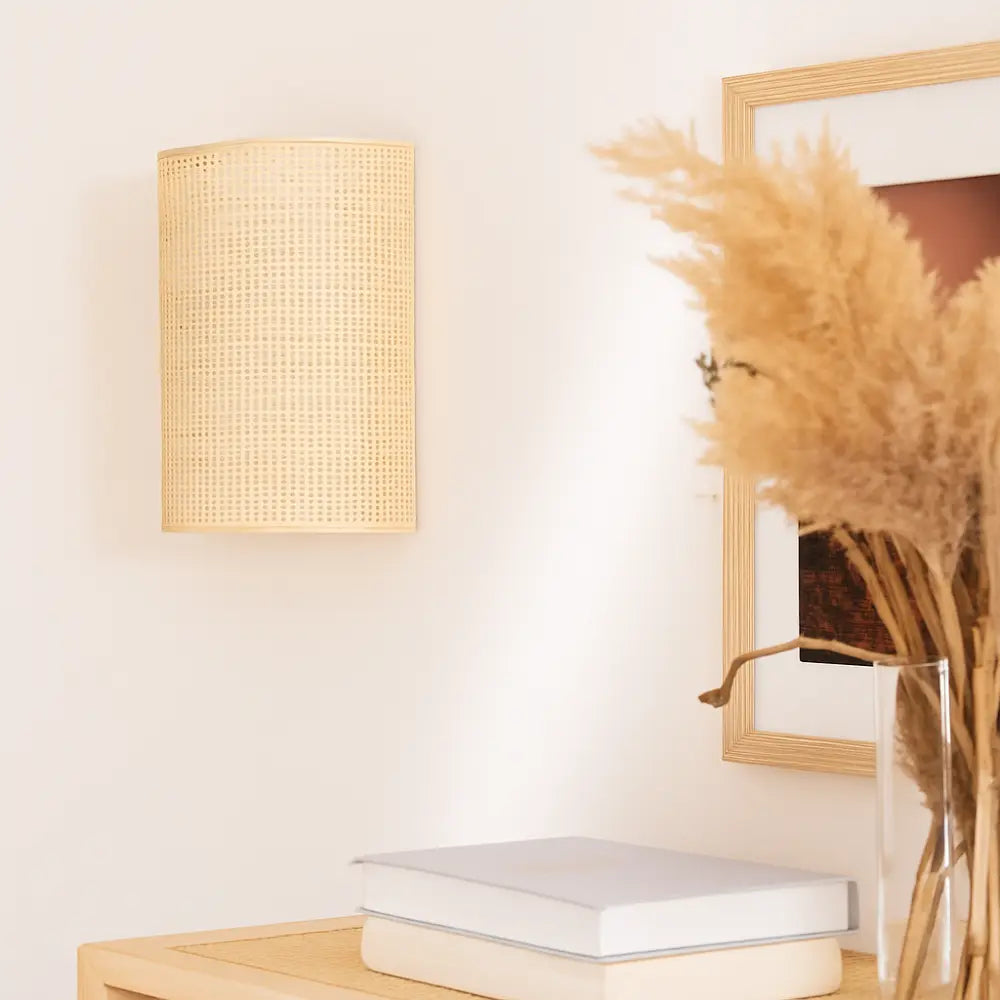 Soft natural rattan wall light casts a warm, inviting Scandinavian glow on the wall.