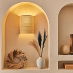 Warm rattan wall light casts a natural, cozy glow against a serene beige backdrop.