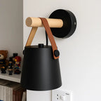 This wall light’s black shade and wood bracket create a stylish, warm glow.