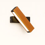 Soft white light glows from an orange diagonal shade, creating a modern luminous accent.