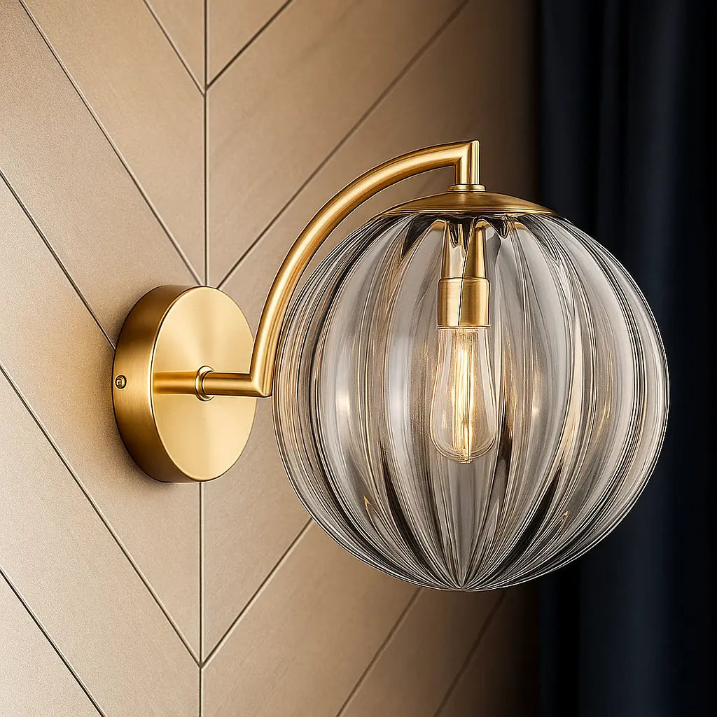 Golden sconce casts a warm glow through its ribbed glass globe and exposed bulb.