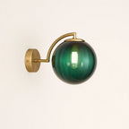 This brass wall light casts a warm, elegant glow through its ribbed glass globe.