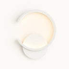 Modern circular wall light with metal crescent frame, round base, and soft LED backglow.
