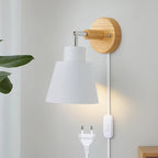 Soft illumination glows from a wooden wall light with a minimalist white shade and cord.