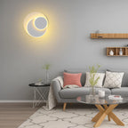 A Modern Adjustable Round LED Metal Wall Sconce glowing softly on a gray wall.