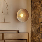 A wavy resin LED wall light in Wabi-Sabi style glows warmly on the wall.