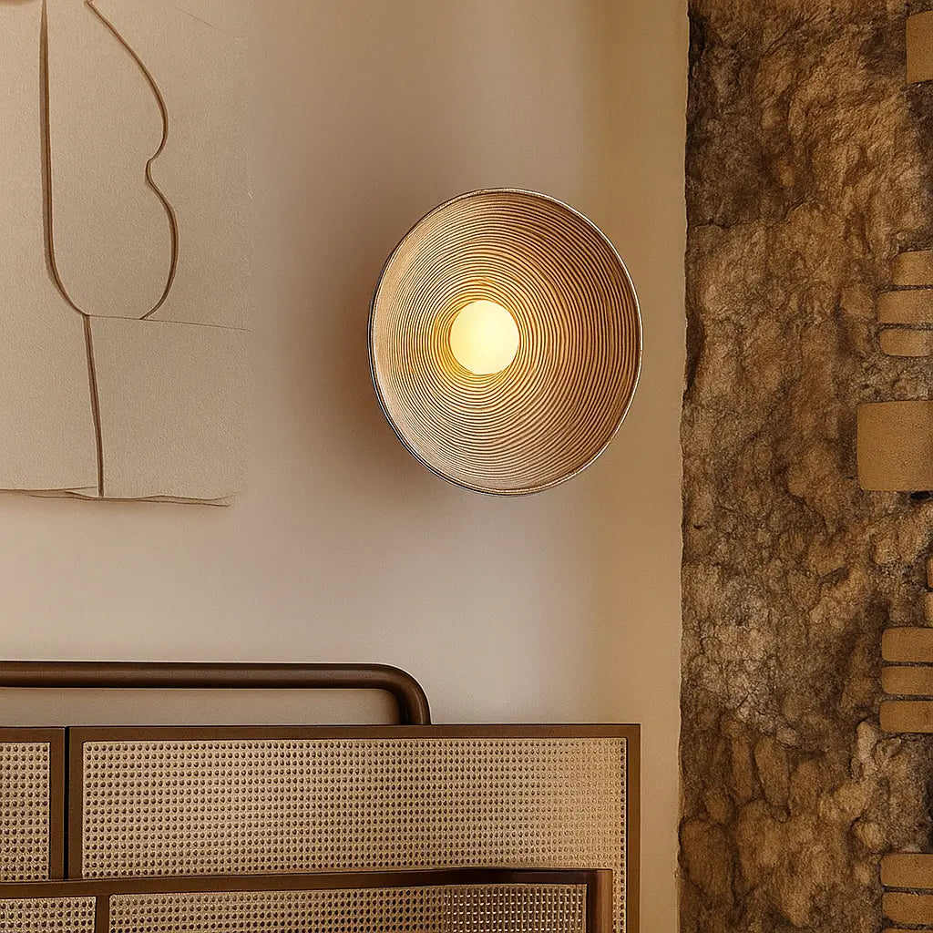 A wavy resin LED wall light in Wabi-Sabi style glows warmly on the wall.
