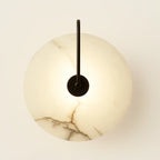 Minimalist circular LED wall lamp with marble-textured glowing shade and central black rod.