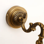 Retro brass gold LED wall light with ornate base, grooved patterns, and curved detailed arm.