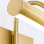 Close-up of brushed gold cylindrical wall sconce with integrated LED, emitting soft white light.
