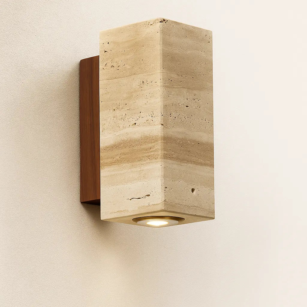 Warm downward LED light glows gently through a round travertine shade and wood backplate.