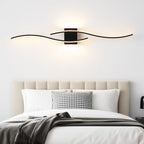 The modern LED wave wall light adds a striking, elegant glow above the bed.