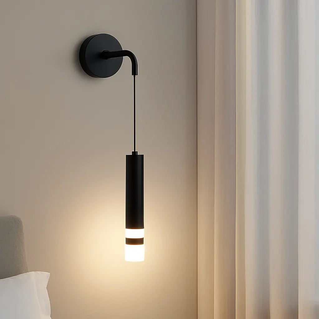Sleek black cylindrical aluminum wall light with integrated LED, emits soft warm glow.