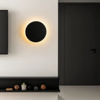 Minimalist Alloy Round LED Wall Light emitting a warm glow against a black and white wall.