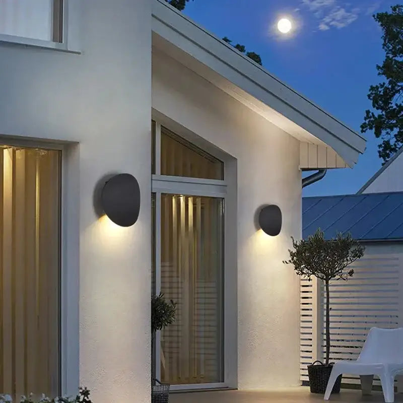 A Round Outdoor Aluminum LED Wall Light emits a warm dusk glow against the modern exterior.