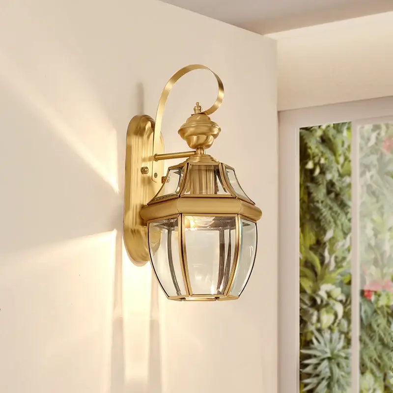 A hexagonal glass and copper retro lantern wall light, mounted and warmly illuminated.