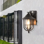 A metal outdoor wall sconce with lantern design, IP65-rated, glowing warmly in rain.