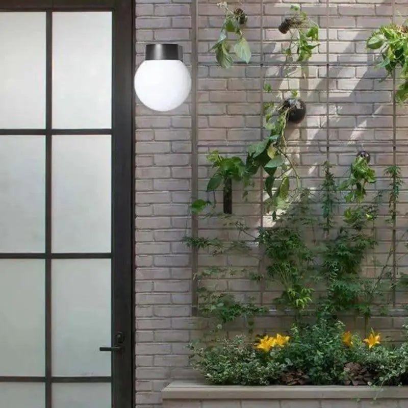 A modern globe acrylic wall light mounted on a brick wall beside a frosted glass door.