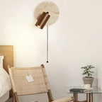 A rounded marble LED wooden wall light with a pull chain, illuminated on the wall.