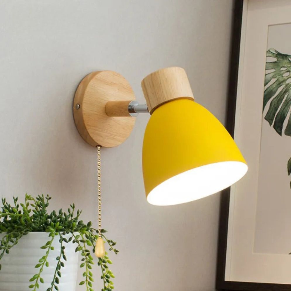 Adjustable yellow metal shade wood wall light with pull chain, LED-compatible, glowing warmly.