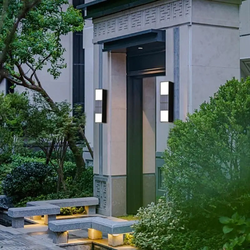Aluminum cylindrical outdoor wall light, modern design, mounted beside a tall dark door.