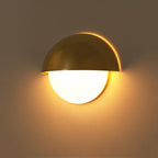 Metallic gold LED wall light emits a warm, soft glow for cozy ambient lighting.