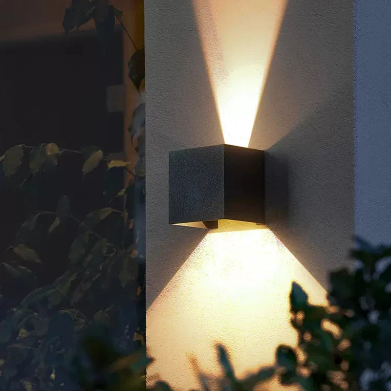 Warm, X-shaped LED beams shine up and down the textured aluminum wall.