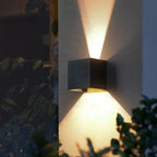 Warm, X-shaped LED beams shine up and down the textured aluminum wall.
