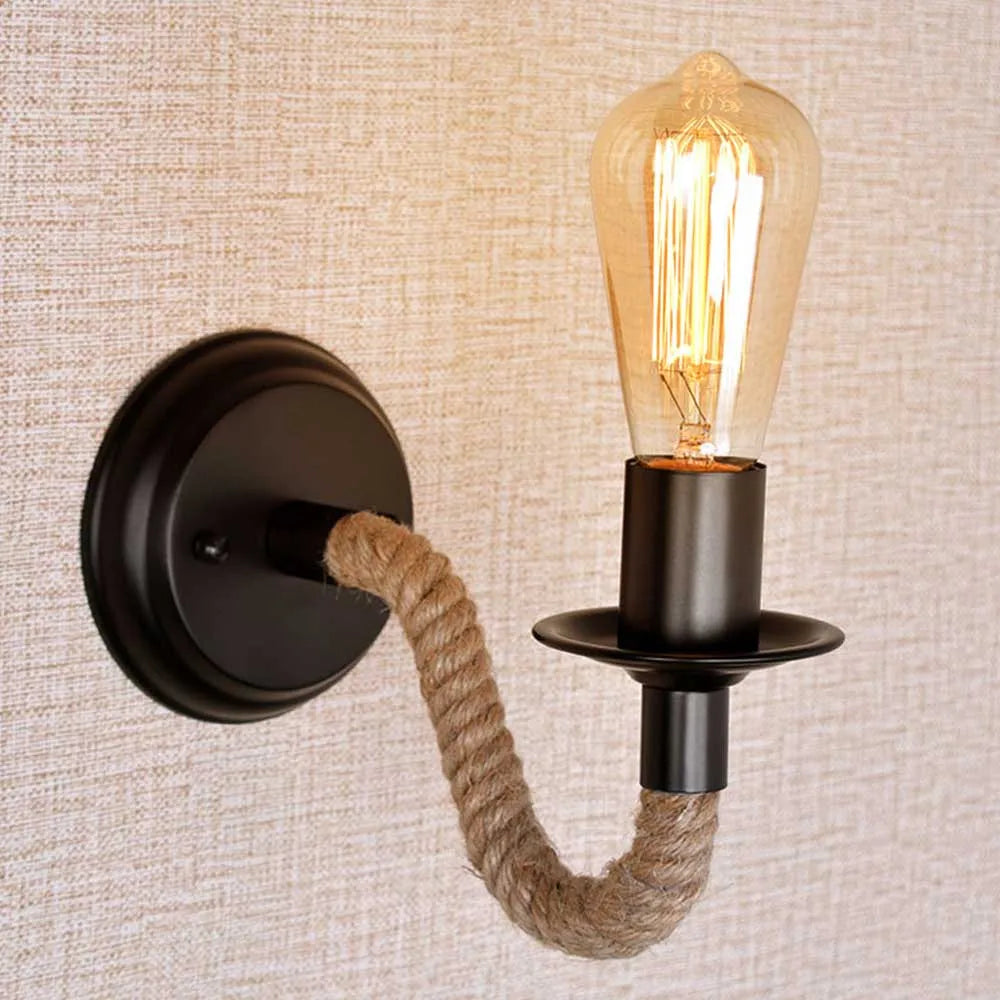 This wall sconce features raw industrial lighting with a visible Edison bulb and bold black base.