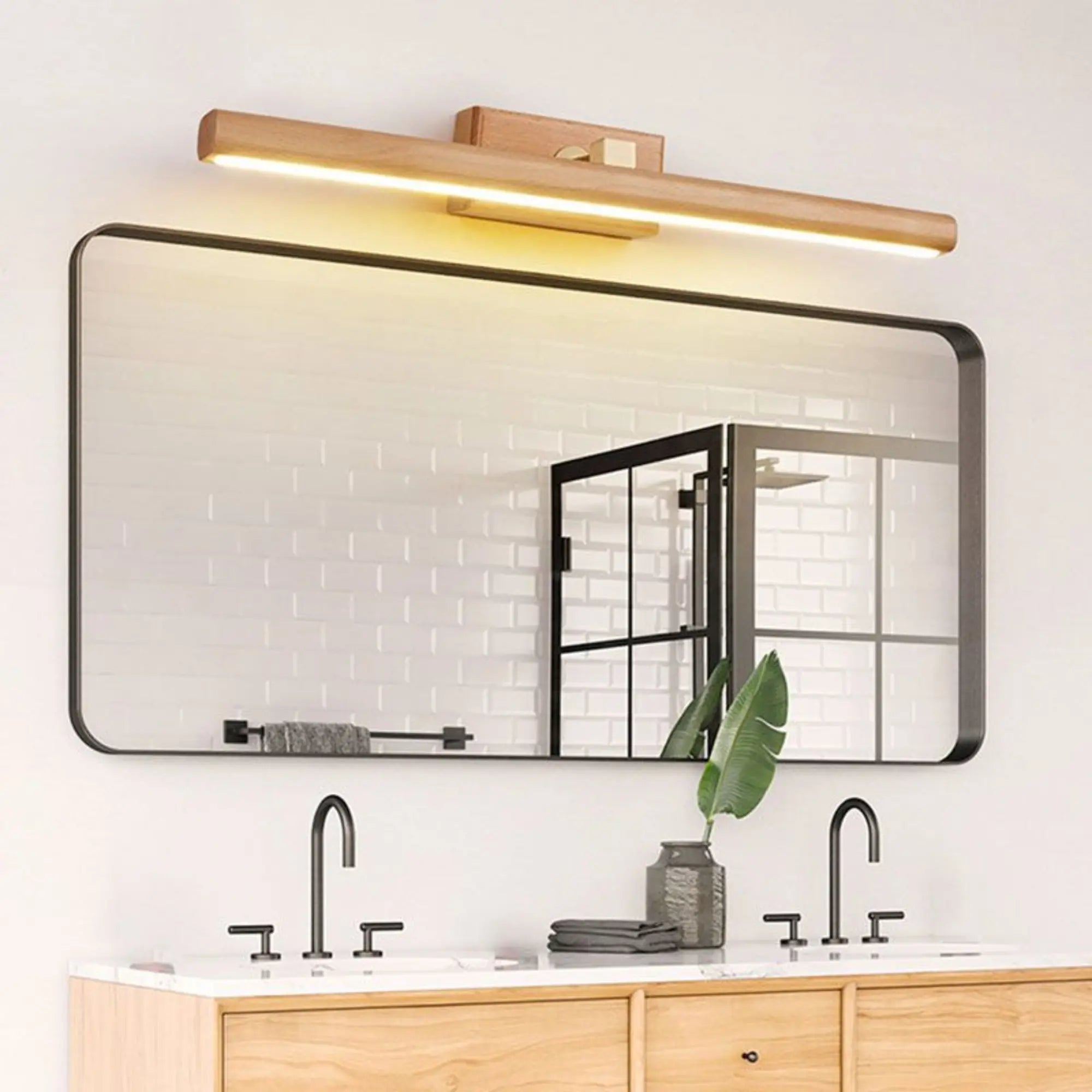 LUMINAIRE MAISON applique murale LED rotative en bois clair installée au-dessus du miroir.