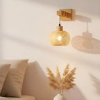 Warm rattan-style wall light casts inviting illumination and decorative shadows on a white wall.