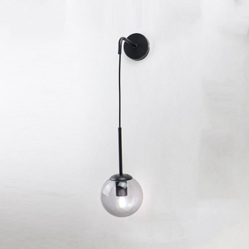 Black and gold wall sconce with spherical glass shade and sleek modern metal design.