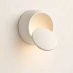 Soft, warm LED light radiates from a sleek, modern circular wall sconce design.