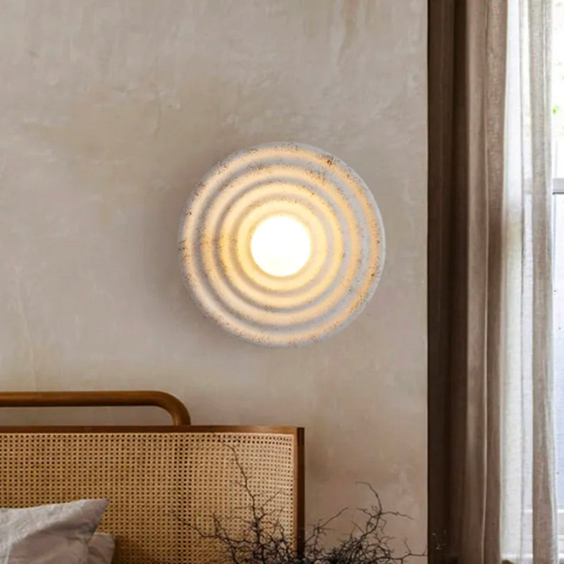 Circular glass wall light with concentric ring patterns, casting a warm, inviting glow.