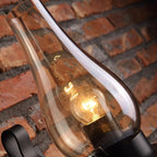 Close-up of vintage industrial glass wall light with transparent shade, illuminated indoors.