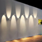 Contemporary LED wall sconce with aluminum body casts overlapping oval beams for decoration.