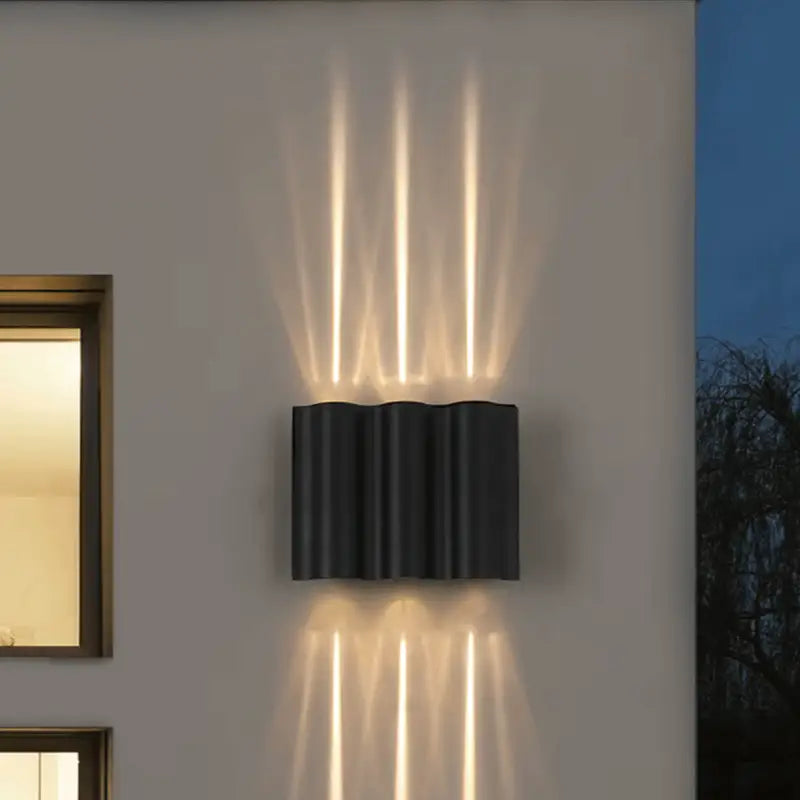 Curved aluminum LED wall light emits soft white beams up and down in artistic patterns.