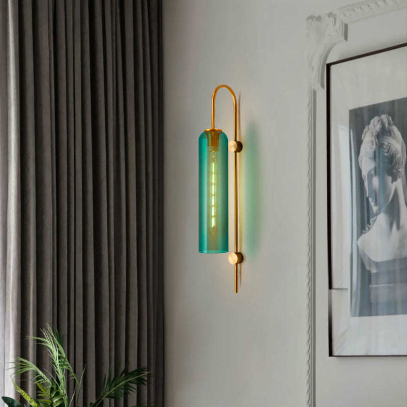 Elegant industrial glass wall light with gold bracket and blue-green shade on white wall.