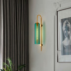 Elegant industrial glass wall light with gold bracket and blue-green shade on white wall.