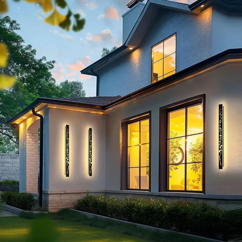 Engraved Floral Aluminum Outdoor Wall Sconce illuminated at dusk on a modern house exterior.