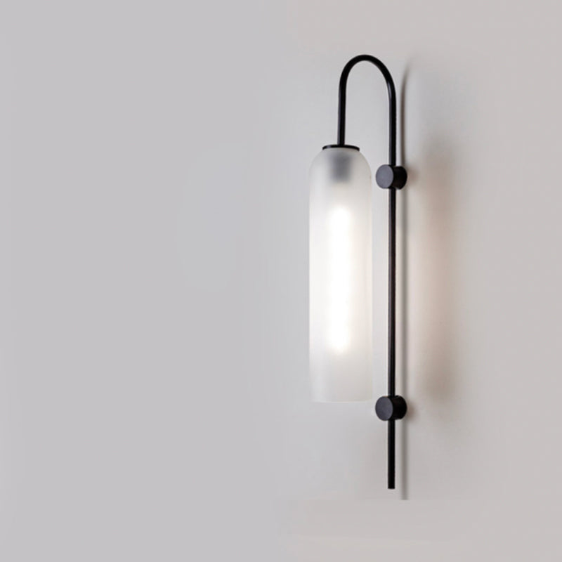 Frosted cylindrical glass wall light with black metal frame, modern industrial style, soft glow.