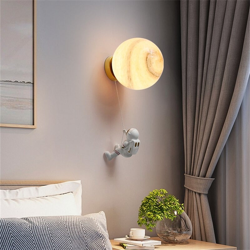 Glowing moon-shaped wall light with a tiny astronaut hanging above, celestial-themed design.