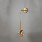 Gold and black wall sconce with a downward clear glass globe shade, modern metal design.