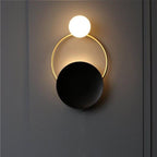 Brushed steel circular wall light with glowing bulb, illuminated ring, and dark disc design.